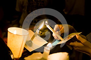 People lighting candle vigil in darkness seeking hope, worship, photo
