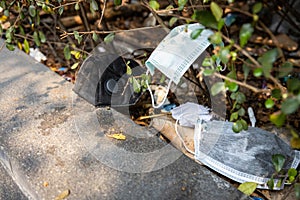 People littering of garbage of used medical masks throw in the crevices of the bushes,hazardous waste,risk of disease,spread of