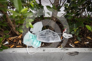 People littering of garbage of used medical masks throw in the crevices of the bushes,hazardous waste,risk of disease,spread of