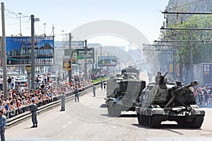 People looks on weaponry and tank on road