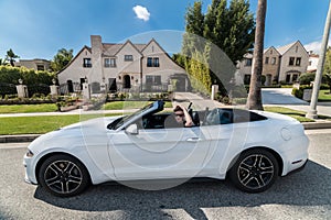 People luxury lifestyle concept. Young adult man driving convertible car in luxury houses neighborhood