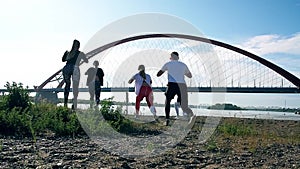 People, man and woman doing exercises on beach at  beautiful day. Group of girls  and boys training. Fitness group.