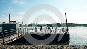 People, man and woman doing exercises on beach at  beautiful day. Group of girls  and boys training. Fitness group.