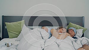 People, a man and a woman are sleeping in bed with their arms around each other.