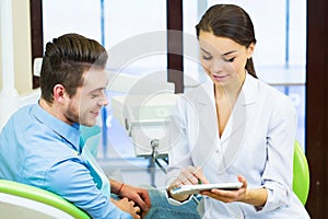 People, medicine, stomatology and health care concept - female dentist showing teeth x-ray scan on tablet pc computer screen to ma