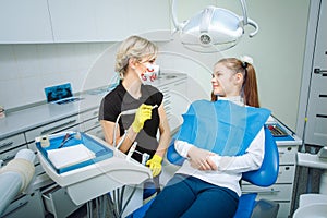 People, medicine, stomatology and health care concept - happy female dentist checking patient teen girl teeth up at