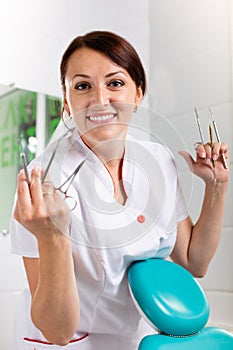 People, medicine, stomatology and healthcare concept - happy young female dentist with tools over medical office