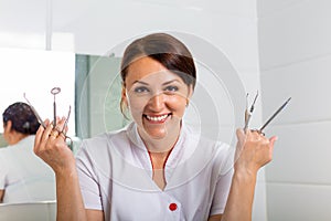 People, medicine, stomatology and healthcare concept - happy young female dentist with tools over medical office