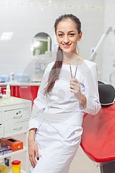 People, medicine, stomatology and healthcare concept - happy young female dentist with tools over medical office