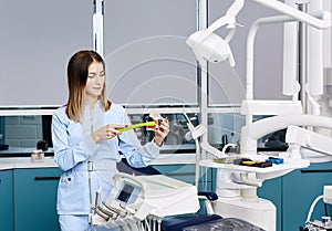 People, medicine, stomatology and healthcare concept - happy young female dentist with tools over medical office