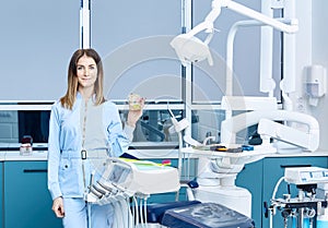 People, medicine, stomatology and healthcare concept - happy young female dentist with tools over medical office