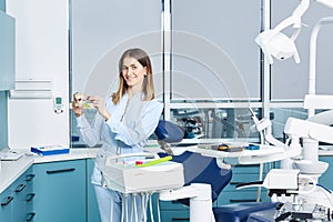 People, medicine, stomatology and healthcare concept - happy young female dentist with tools over medical office