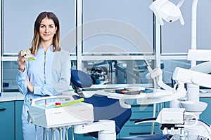 People, medicine, stomatology and healthcare concept - happy young female dentist with tools over medical office