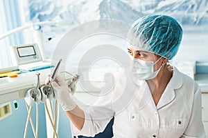 People, medicine, stomatology and healthcare concept - happy young female dentist with tools over medical office