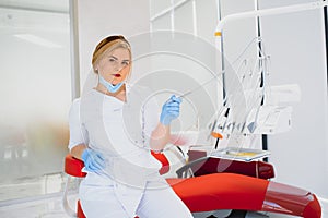 People, medicine, stomatology and healthcare concept - happy young female dentist with tools over medical office background