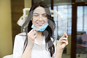 People, medicine, stomatology and healthcare concept - happy young female dentist with tools over medical office background
