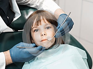 People, medicine, stomatology, technology and health care concept. Male dentist working with little girl in clinic.