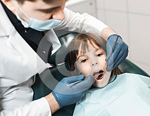 People, medicine, stomatology, technology and health care concept. Male dentist working with little girl in clinic.