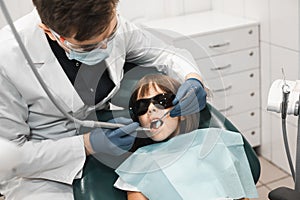 People, medicine, stomatology, technology and health care concept. Male dentist working with little girl in clinic.