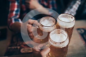 People, men, leisure, friendship and celebration concept - happy male friends drinking beer and clinking glasses at bar or pub