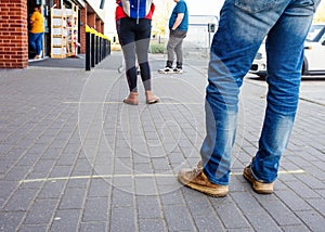 People men and women in a line / queue at the supermarket / mall  at a social distance during the quarantine / epidemic