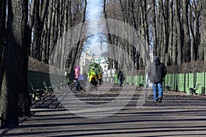 People, men, women with strollers walking along the path in the