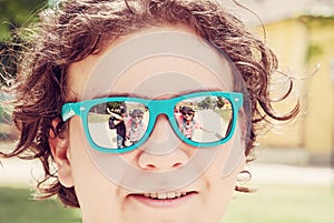 People are mirroring in sunglasses of teenage boy