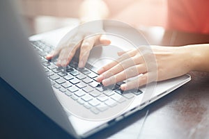 People and modern technology concept. Close up shot of female hands typing on keyboard of her laptop. Young businesswoman working