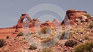 People move around Delicate Arch exploring the desert landscape