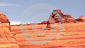 People move around Delicate Arch exploring the desert landscape