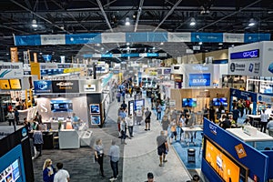 People moving amongst trade show booths in a crowded convention hall, A crowded trade show floor with booths showcasing the latest