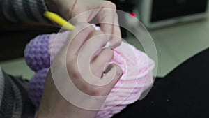 People and needlework concept - woman knitting with crochet hook and pink yarn