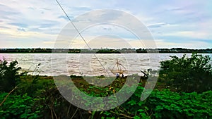 people net fishing using poles on a river with overwhelming water after heavy rain under a cloudy sky