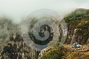 People next to the edge of rocky cliff and mist