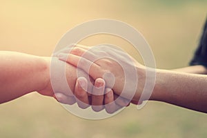 people old and young hand holding with sunset