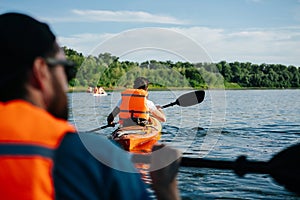 People in orange life jackets kayaking on a big wide river.
