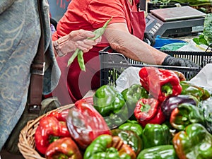 People out of focus, not recognisable in the field. Person buying fresh fruit and vegetables