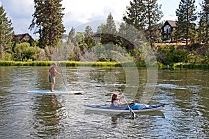 People Paddle Boarding And Canoeing In River