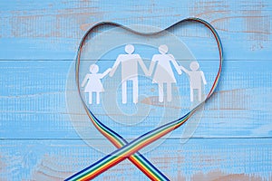 People paper shape with LGBTQ heart shape Rainbow ribbon on blue pastel wooden background for Lesbian, Gay, Bisexual, Transgender