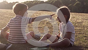 people in the park. happy family silhouette sitting on grass at sunset. mom with three kids eating fruits Grapes snack