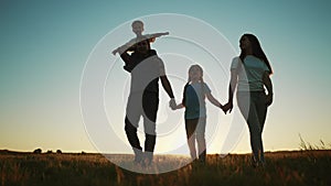 people in the park. happy family walking silhouette at sunset. mom dad and daughters walk holding sun hands in the park