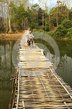 people passing bamboo bridge on limestone mountain background