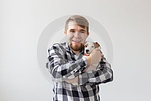 People, pet and dog concept - Smiling man over white background holding puppy Jack Russell Terrier