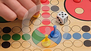 People play Ludo or Pachisi board game on beautiful wooden play board. Ludo is a strategy board game for two to four