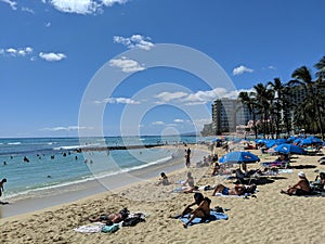 People play in the protected water and hang out on the beach in Waikiki