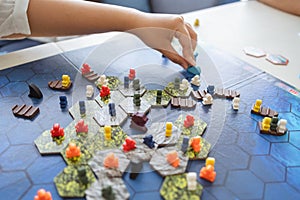 People playing board game on board game field with many figure, meeple, dice, models at home. Playing game with friends, family,