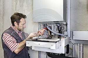 Plumber repairing a condensing boiler photo