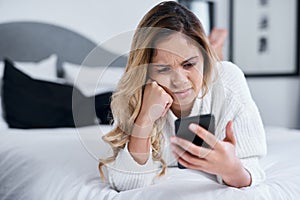 People post the weirdest stuff. a young woman using her cellphone while lying on her bed.