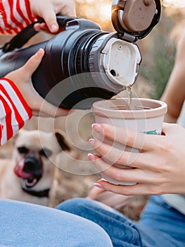 People pour water from a thermos into a mug and dog