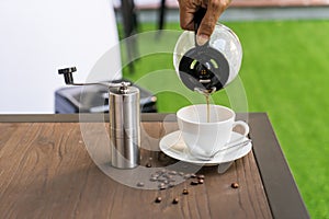 People pouring coffee in  cup beside Coffee grinder